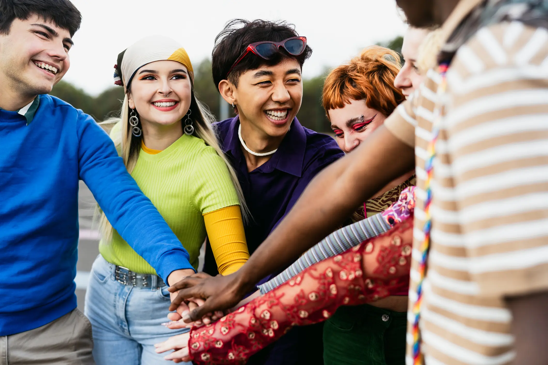 Happy young diverse friends having fun stacking hands together outdoor – Youth people millennial generation concept Pride Program