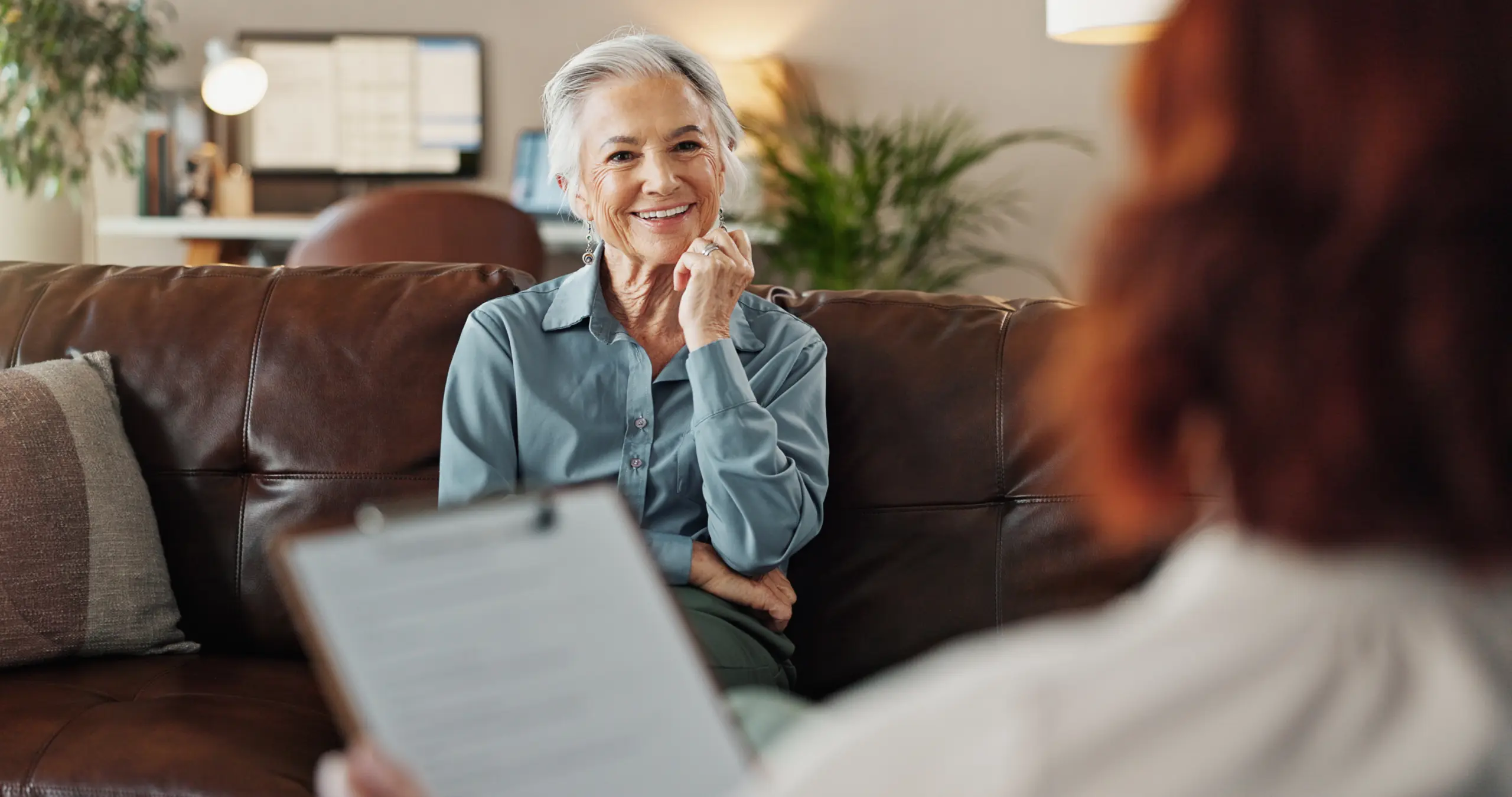 Psychologist, clipboard and senior woman with smile and office from mental health assessment in consultation. Help, support and care with counseling, psychology and evaluation with advice in office Addiction Treatment