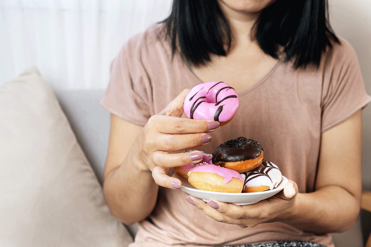 a woman holds a dish of donuts